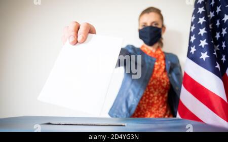 femme portant un masque mettant le vote au scrutin Banque D'Images