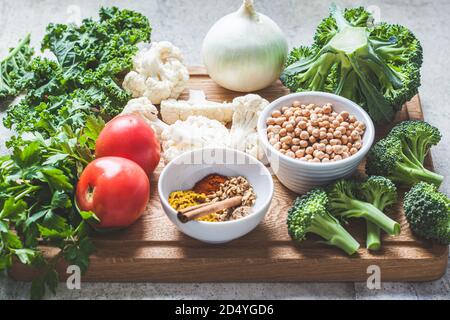 Fond de cuisson avec des légumes frais, des épices et des haricots. Ingrédients crus pour la cuisson du curry végétarien avec des légumes et des pois chiches sur un boa bois Banque D'Images