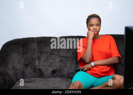 La jeune femme africaine s'est ennuyé avec ce qu'elle regarde à la télévision Banque D'Images