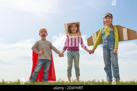 Les enfants en costumes d'astronaute, de pilote et de super héros rient, jouent et rêvent. Portrait des enfants amusants sur la nature. Jeux pour amis en famille outdoo Banque D'Images