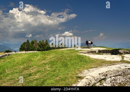 Les touristes admirent le paysage depuis le sommet de Cima Campo, Arsiè, Belluno. Prairie verte et arbres dans un ciel couvert de nuages Banque D'Images