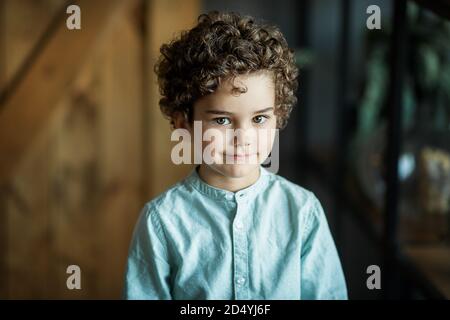 portrait d'un garçon curly sur fond sombre Banque D'Images