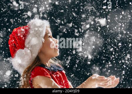 Un miracle de Noël! bonne petite fille attrapant des flocons de neige dans ses mains Banque D'Images