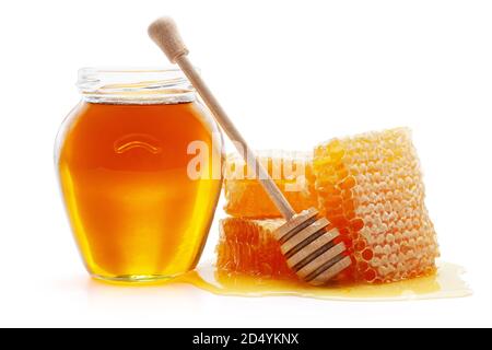 Miel dans un pot en verre avec un balancier en bois et des alvéoles, isolé sur fond blanc, passe de tonte inclus. Banque D'Images