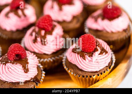 Des cupcakes au chocolat gourmets, arrosés de ganache au chocolat et recouverts d'une framboise fraîche. Banque D'Images