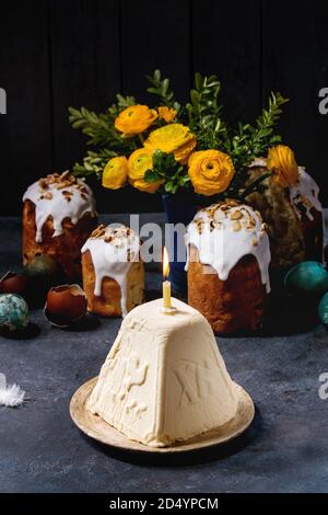 Pâques russe traditionnel dessert fromage cottage, orthodoxe Paskha avec bougie brûlante debout dans une plaque en céramique sur table avec texture sombre kulich cak Banque D'Images