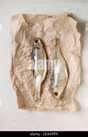 Le poisson séché ou stockfish sur papier froissé sur fond de marbre blanc. Mise à plat, de l'espace Banque D'Images