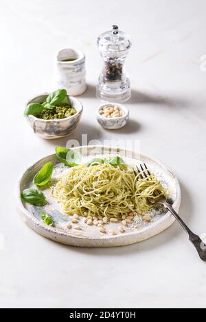 Les pâtes spaghetti italien classique au pesto, pignons de pin, huile d'olive et de basilic frais. Servi dans une plaque en céramique avec fourchette et les ingrédients ci-dessus plus de w Banque D'Images