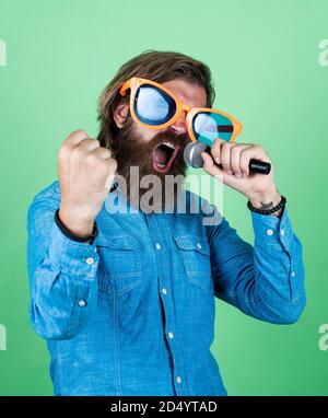 Musique moderne. hipster homme avec des lunettes de barbe. Concept musical. Passez de bonnes vacances. Amusez-vous à la fête. Chant de chanteur masculin dans le microphone. Fêtez l'anniversaire. Fêtez votre fête. Banque D'Images