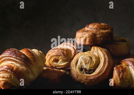 Variété de pâte feuilletée faite maison à la cannelle brioches et croissants. La vie encore sombre. Close up Banque D'Images