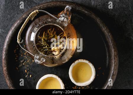 Thé vert chaud dans deux chinois traditionnels et tasse en céramique argile ouvert théière en verre dans le bac sur fond de marbre noir. Télévision lay, Close up Banque D'Images