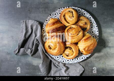Variété de pâte feuilletée faite maison à la cannelle brioches et croissants servis dans une plaque en céramique bleu sur fond de texture. Mise à plat, de l'espace Banque D'Images