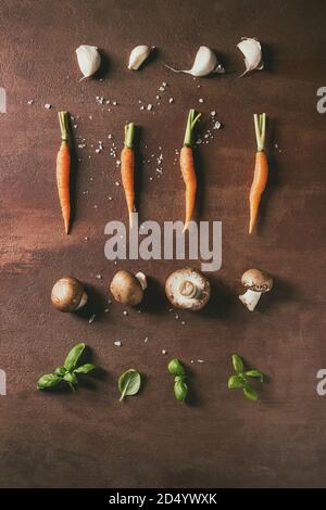 Herbes basilic frais avec mini-carottes et champignon champignons en ligne sur fond brun. Mise à plat, de l'espace. Concept de cuisine, de l'alimentation arrière-plan. Banque D'Images