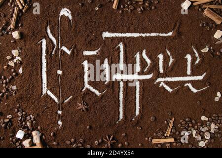 Inscription calligraphique lettres gothiques sur café café noir éparpillés sur du marbre blanc avec des haricots, du sucre et de la cannelle. Boire du café Banque D'Images