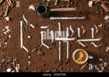 Inscription calligraphique lettres gothiques sur café café noir éparpillés sur de marbre blanc avec des haricots rôtis, pot, tasse d'espresso. Dri Café Banque D'Images
