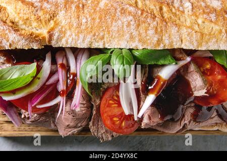 Close up of beef sandwich baguette avec tomates, basilic, oignon rouge. Mise à plat, de l'espace Banque D'Images