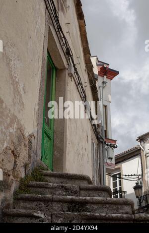 Marches en pierre menant à l'ancienne porte en bois vert dans la petite ville de Galice, Espagne. Porte entrée ville architecture escalier de pierre espagnol. Banque D'Images