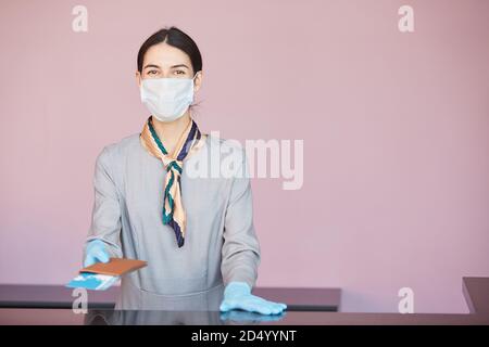 Portrait à la taille de l'accompagnateur souriant portant un masque lorsqu'il se trouve au comptoir d'enregistrement, en train de remettre des billets au passager, dans l'espace de photocopie Banque D'Images