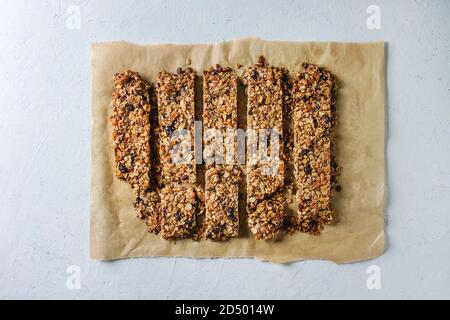 L'avoine énergétiques maison coupe les barres granola aux fruits secs et les noix sur du papier sulfurisé sur fond blanc texture background. Collation santé. Mise à plat, de l'espace Banque D'Images