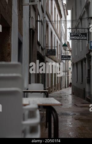 Saint-Jacques-de-Compostelle, Galice, Espagne - 09/26/2020: Chaises et tables en plastique empilées dans une petite rue vide de l'auberge avec un café fermé. Banque D'Images