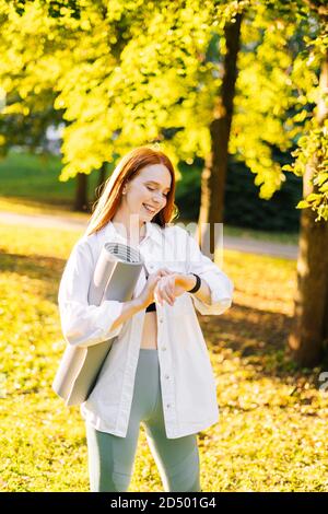 Riant mignonne rouge-cheveux jeune femme regardant le sport montre intelligente, Banque D'Images