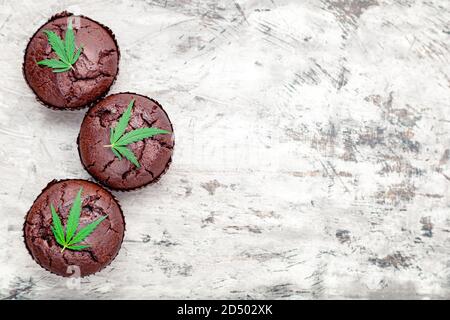 Muffins au chocolat et au cupcake avec du cannabis laisse l'herbe cbd. Médicaments marijuana chanvre drogues dans le dessert alimentaire. Cuisson des muffins aux mauvaises herbes avec de la marijuana Banque D'Images