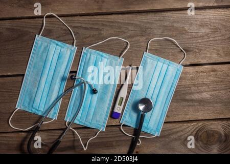 .masques médicaux, stéthoscope et thermomètre sur fond de bois Banque D'Images