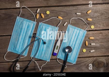.masques médicaux, stéthoscope et thermomètre sur fond de bois Banque D'Images