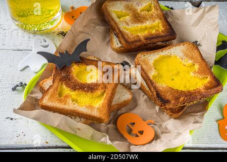 Nourriture drôle pour les enfants, petit déjeuner Halloween, boîte à déjeuner: Toast avec des œufs brouillés en forme de monstres et fantômes Halloween, sur table en bois avec déc Banque D'Images