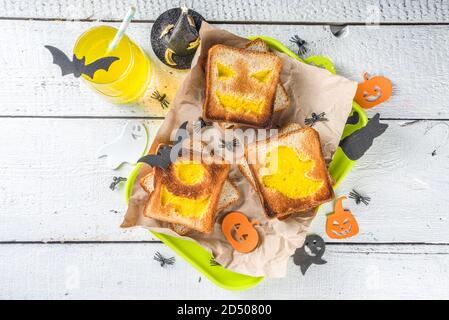 Nourriture drôle pour les enfants, petit déjeuner Halloween, boîte à déjeuner: Toast avec des œufs brouillés en forme de monstres et fantômes Halloween, sur table en bois avec déc Banque D'Images