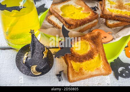 Nourriture drôle pour les enfants, petit déjeuner Halloween, boîte à déjeuner: Toast avec des œufs brouillés en forme de monstres et fantômes Halloween, sur table en bois avec déc Banque D'Images