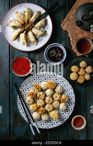 Les Gyozas dim sum dumplings frits asiatique partie fixe avec variété de sauces servis dans des assiettes en céramique et des bols avec des baguettes, tasses à thé et une théière sur dar Banque D'Images