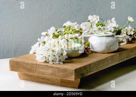 Fait main artisanat théière et tasse en céramique avec du thé chaud décoré par des branches de cerisier en fleurs au printemps sur le plateau de service en bois de style japonais sur blanc en t Banque D'Images