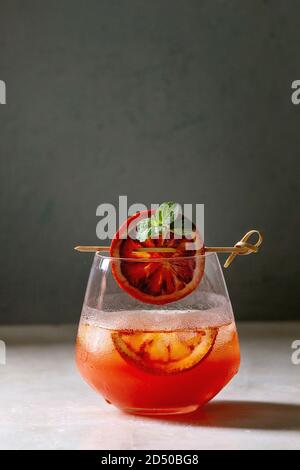 Orange sanguine cocktails glacés en verre, décorée par tranche d'orange et menthe fraîche sur brochette, servi sur la table de marbre blanc avec du gris au mur backgroun Banque D'Images