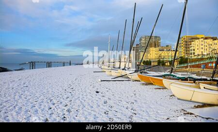 Petits bateaux à voile sur une plage de galets sur une gelée matin enneigé Banque D'Images