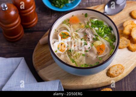 Soupe avec poulet, nouilles, pommes de terre, œufs de caille et carottes. Assaisonné d'oignons et de persil. Gros plan. Banque D'Images