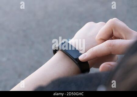 technologies de communication concept-gros plan une femme ajuste une montre intelligente, avant la course, au-dessus de l'épaule. Banque D'Images