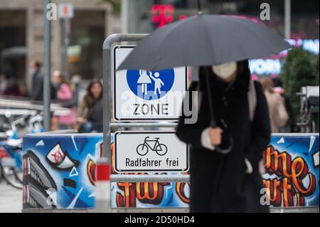 12 octobre 2020, Baden-Wuerttemberg, Stuttgart: Un passant avec une protection de la bouche et du nez marche sous un parapluie après une entrée de la zone piétonne dans le centre-ville. À Stuttgart, la valeur d'avertissement de 50 nouvelles infections pour 100 000 habitants en sept jours a été dépassée le samedi 10 octobre 2020. À partir du mercredi 14.10, les masques seront obligatoires dans le centre-ville, à l'intérieur de l'anneau de la ville. Photo: Sebastian Gollnow/dpa Banque D'Images