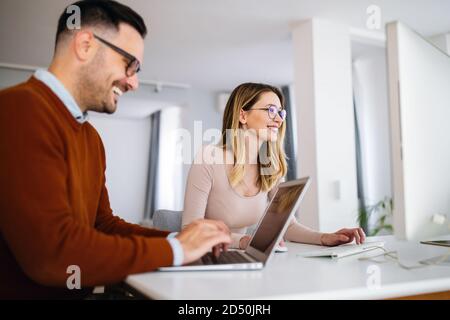 Graphistes travaillant au bureau avec un ordinateur portable. Équipe discutant des idées dans l'agence de publicité. Banque D'Images