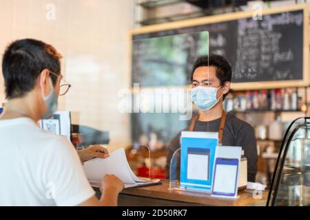 Nouveau client de service de serveur normal au comptoir de café avec protection de partition. Banque D'Images