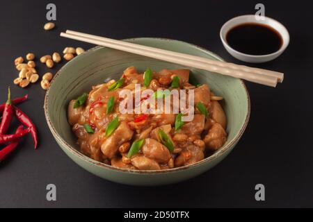 Poulet kung Bao sur fond noir. Un plat chinois avec du poulet, du piment, des arachides, des sauces et des oignons. Banque D'Images