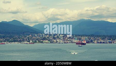 Vue sur le port de Vancouver au Canada, vu de l'eau. Avec des cargos, des gratte-ciel et des montagnes vallonnés en arrière-plan. Banque D'Images