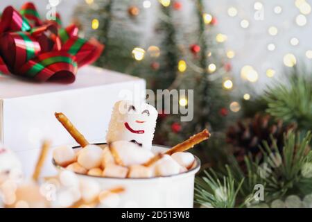 Deux bonshommes de neige qui se trempent dans une tasse de chocolat chaud entourée de mini guimauves. Mise au point extrême sélective avec un premier plan et un arrière-plan flous. Noël t Banque D'Images