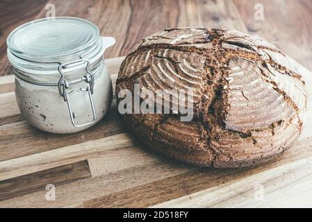 pain au levain de seigle maison fraîchement cuit et entrée au levain pot sur table en bois Banque D'Images