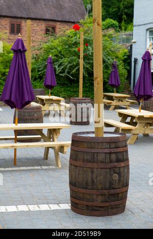 gros plan de tables et chaises en bois vides avec fermé parasols violets à l'extérieur du restaurant avec des mesures de distance sociales en automne Banque D'Images