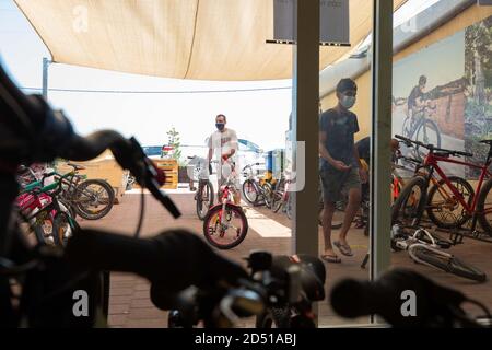 Boutique de vélos pendant la pandémie COVID-19. Les clients attendent à l'extérieur du petit magasin pour le service et sont servis à la porte. Les clients sont obligés de wea Banque D'Images