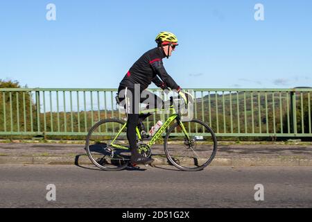 Cycliste de sexe masculin à bord d'un vélo de route sport en fibre de carbone Cannondale sur une route de campagne traversant un pont autoroutier dans la région rurale du Lancashire, au Royaume-Uni Banque D'Images