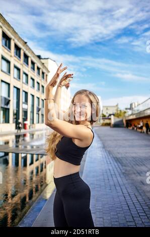 Belle femme danseuse aux longs cheveux blonds posant sur la rue de la ville. Improvisation dansante féminine - danse latine, tango, contemporaine et bachata Banque D'Images