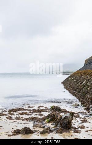 Vue sur le mur de la jetée au niveau de la mer lors d'une journée calme et brumeuse à Old Head, Louisburgh, comté de Mayo, Irlande Banque D'Images