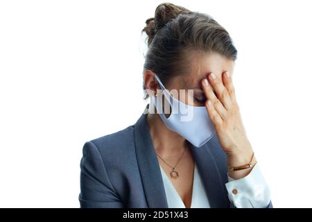 Les affaires pendant la pandémie de coronavirus. Stressé moderne d'âge moyen femme d'affaires dans un costume gris avec masque médical sur fond blanc. Banque D'Images